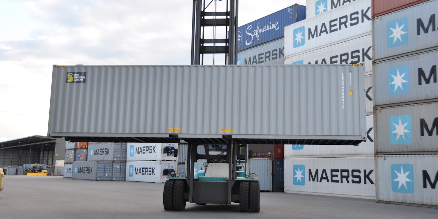 Forty feet shipping container on forklift with shipping containers in background