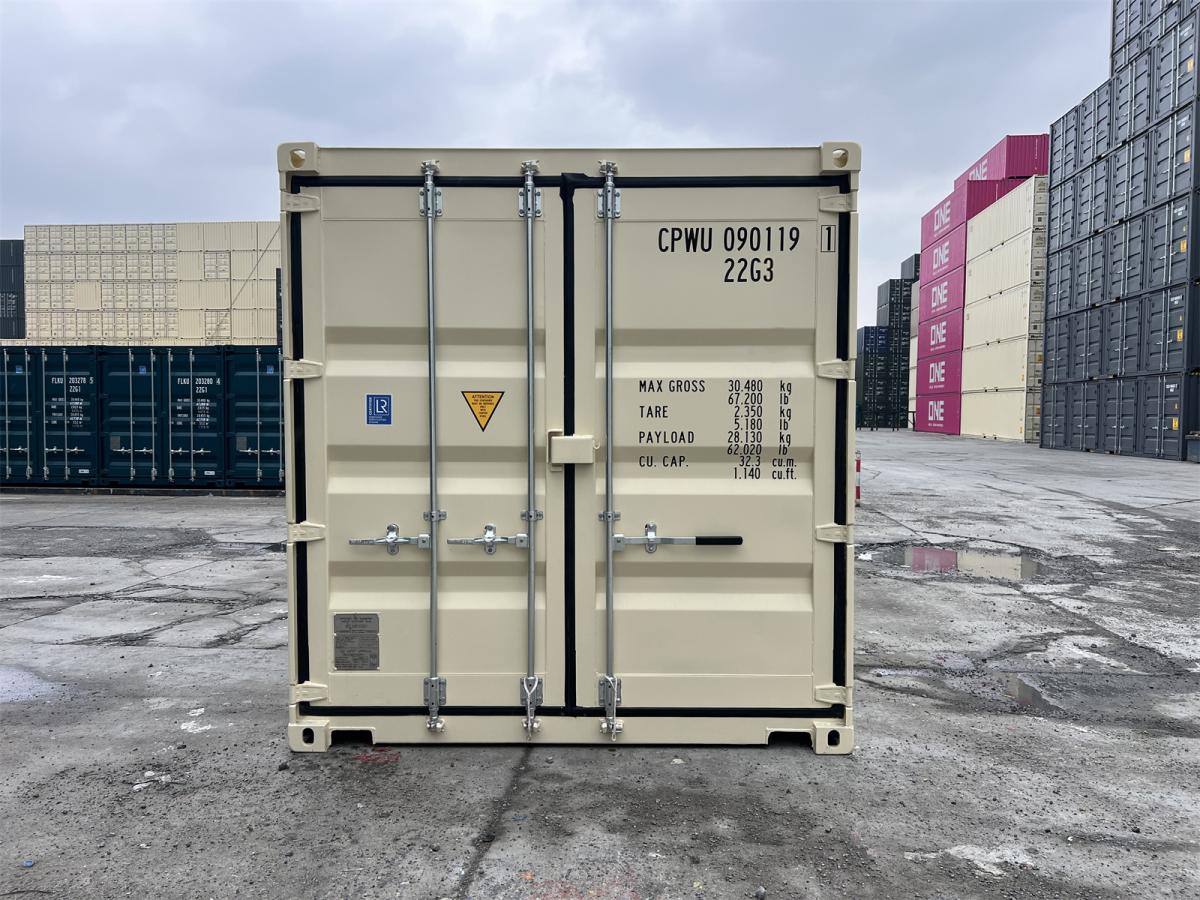 A straight-on, eye-level shot of the closed rear doors of an ivory-colored shipping container in a shipyard. The door features black rubber seals, silver locking bars, and detailed technical specifications printed in dark gray, including the container code "CPWU 090119 1" and "22G3".