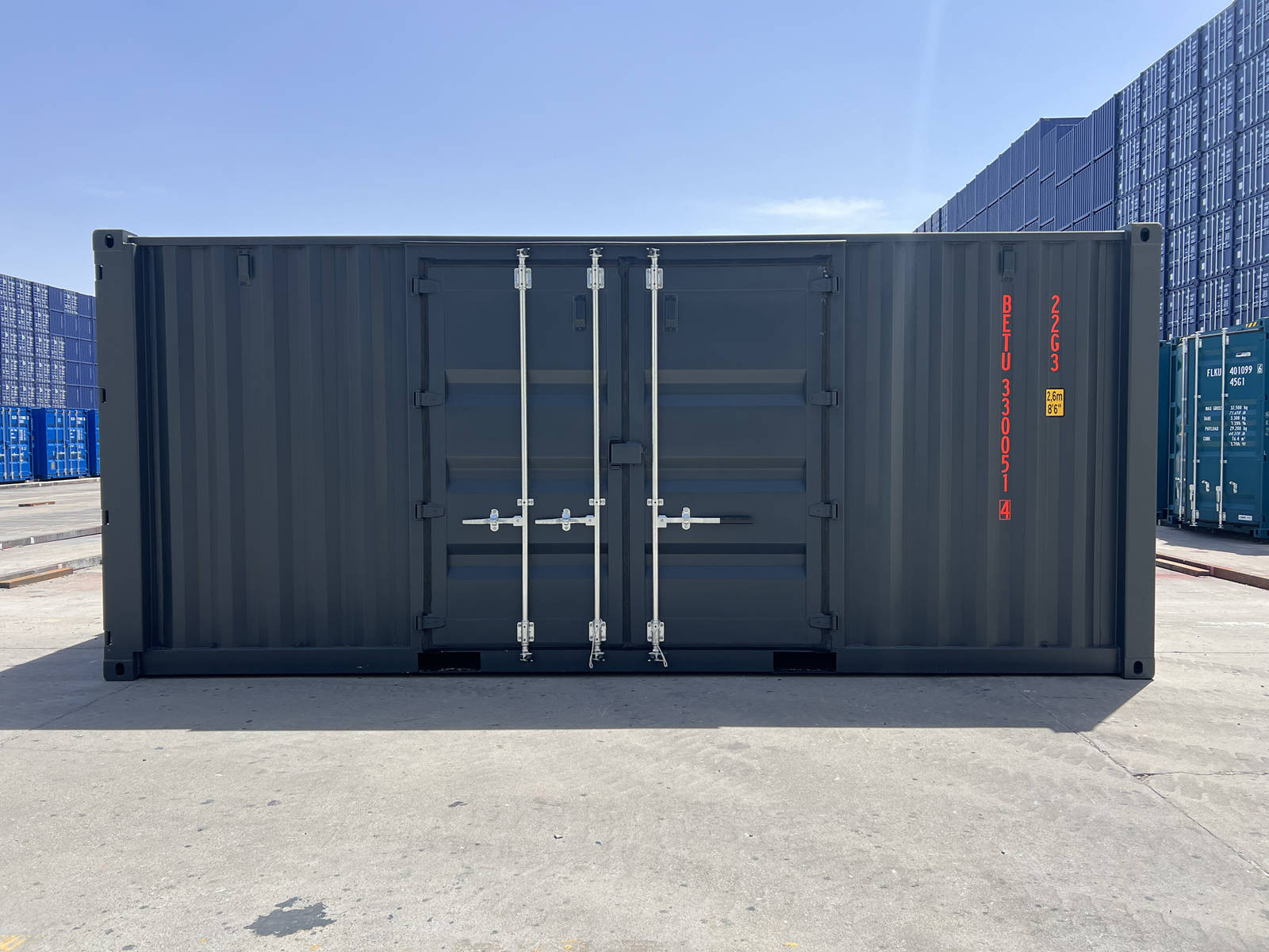 A direct, wide side view of the dark gray shipping container showing the closed side double doors. The container code "BETU 330051 4" and a height warning label are printed vertically in orange on the right side of the panel.